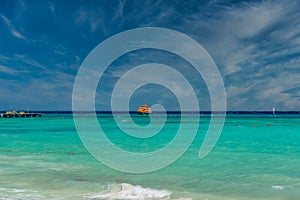 Orange ferry in azure ocean with swimming people in Playa del Carmen, Yukatan, Mexico