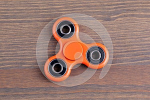 Orange fidget spinner stress relieving toy on wood background