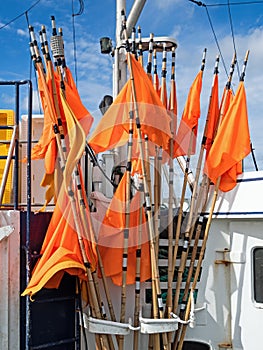 Orange flags marking fishing nets on board a fishing boat in the harbor of Hanstholm, Denmark