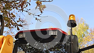Orange flasher on a construction equipment tractor excavator on a sky background. Road repair and construction concept