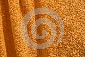 Orange fleecy fabric. Dry towel with folds.