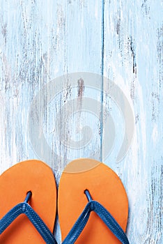 Orange flip-flops on a blue rustic wooden surface