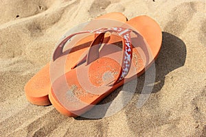 Orange flip-flops on the sand