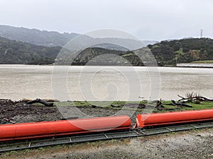 Orange floating debris boom, barrier on ground of reservoir during the rainy season