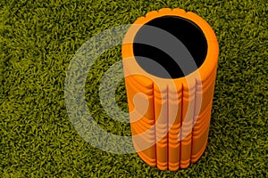 Orange foam roller on green background