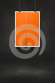 Orange folded poster hanging on a black wall with clips