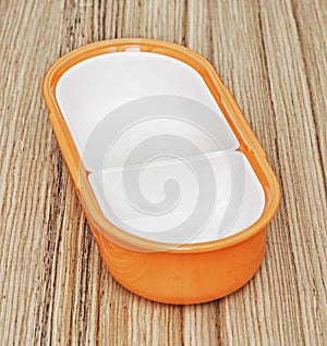 Orange folding plastic food box on the wooden background, kitchen equipment