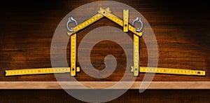 Orange Folding Ruler in the Shape of a House Hanging on a Wooden Wall