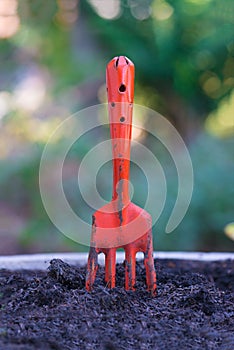 Orange fork harrows on black soil ground. background and texture