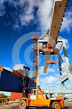 Orange forklift and crane at loading and unloading of cargo in t