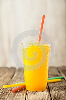Orange Frozen Slushie in Plastic Cup with Straw photo