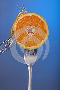 Orange fruit fork water splash blue concept health