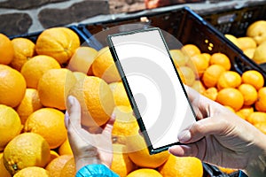 Orange fruit in hand and smartphone isolated white