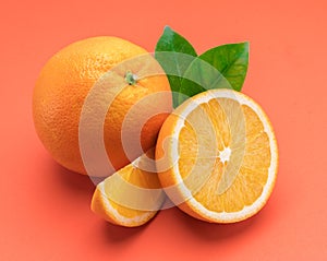 Orange fruit with orange slices and leaves isolated on orange background