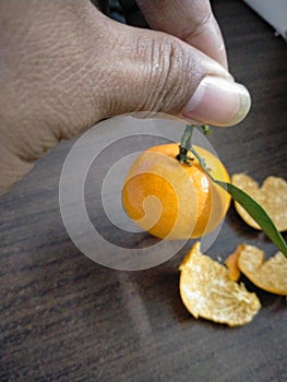 The orange fruit and peel are occurring in the wooden table