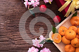 Orange fruit, pink cherry blossom and Chinese new year composition set on wood table, Chinese new year celebration background