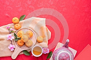 Orange fruit, Pink cherry blossom and teapot with Copy space for text on red texture background, Concept of Chinese new year