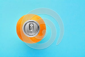 Orange fruit with pop up silver top of a can on blue background with copy space