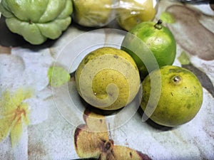 orange fruit with yellowish green skin on a patterned table photo