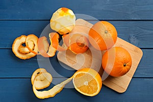 Orange fruits with peels on blue wooden table, flat lay