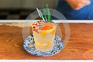 The orange fruity cocktail that mix with sliced orange and pomegranate pulps in a drinking glass. Decorated with banana leaves
