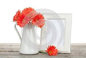 Orange gerbera flowers and photo frame on wooden table