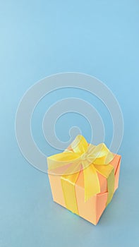 An orange gift box on a blue background, copy space, vertical.