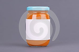 Orange glass jar for baby food bank on grey background. Organic baby food puree. Mock up without template design label.