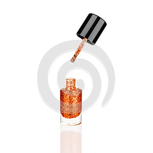 Orange glittering nail polish glass bottle, brush white background isolated closeup, opened red sequin varnish, shiny lacquer