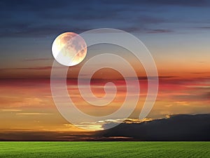 Full moon night sky ,gold sunset sunbeam ,dramatic fluffy clouds at evening sky  and green grass on field  nature lands