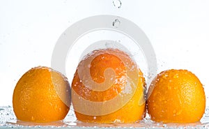 Orange and grapefruit in a spray of water on a white background