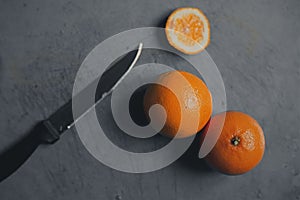 Orange on grey chopping board with knife