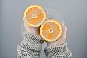 Orange half cut 2 pieces on women hands with sweater on light grey background. horizontal image