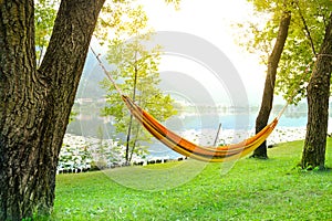 Orange hammock tied to the trees by the lake to relax