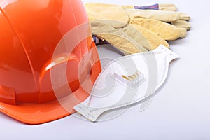 Orange hard hat, goggles, protective mask, respirator and safety gloves on a white background.
