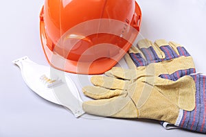 Orange hard hat, goggles, protective mask, respirator and safety gloves on a white background.