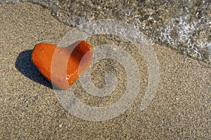 Orange heart shaped stone at the beach