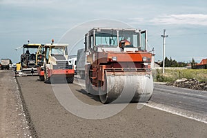 Orange Heavy Vibration roller compactor at asphalt pavement works for road repairing. Working on the new road