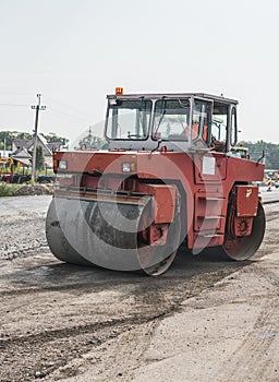 Orange Heavy Vibration roller compactor at asphalt pavement works for road repairing. Working on the new road