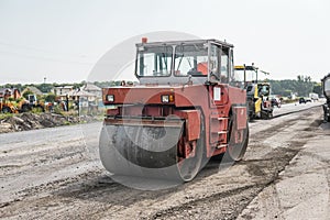 Orange Heavy Vibration roller compactor at asphalt pavement works for road repairing. Working on the new road