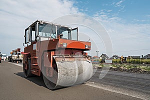 Orange Heavy Vibration roller compactor at asphalt pavement works for road repairing. Working on the new road