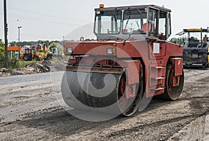 Orange Heavy Vibration roller compactor at asphalt pavement works for road repairing. Working on the new road