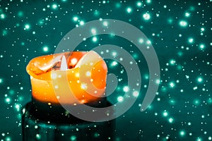 Orange holiday candle on green sparkling snowing background, luxury branding design for Halloween, New Years Eve and Christmas