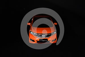 Orange Honda jazz car on dark background.