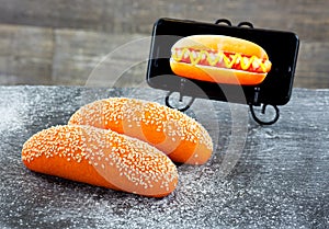 Orange hot dog bun with sesame seeds on a floured stone plate