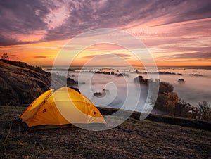 Orange illuminated from inside tent above river at sunset