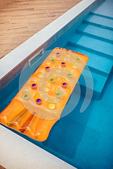 Orange inflatable mattress in the pool