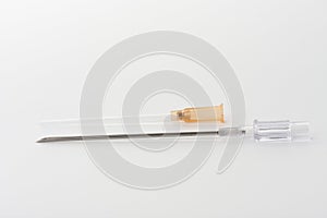 Orange intravenous cannula 14 G on white background, external diameter 2,1 mm, used in trauma, blood transfusion, surgery, ascites