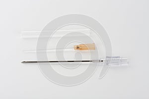 Orange intravenous cannula 14 G on white background, external diameter 2,1 mm, used in trauma, blood transfusion, surgery, ascites