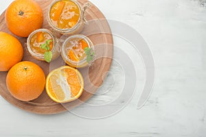 Orange jam in a glass jar on a light background. With an empty space for writing